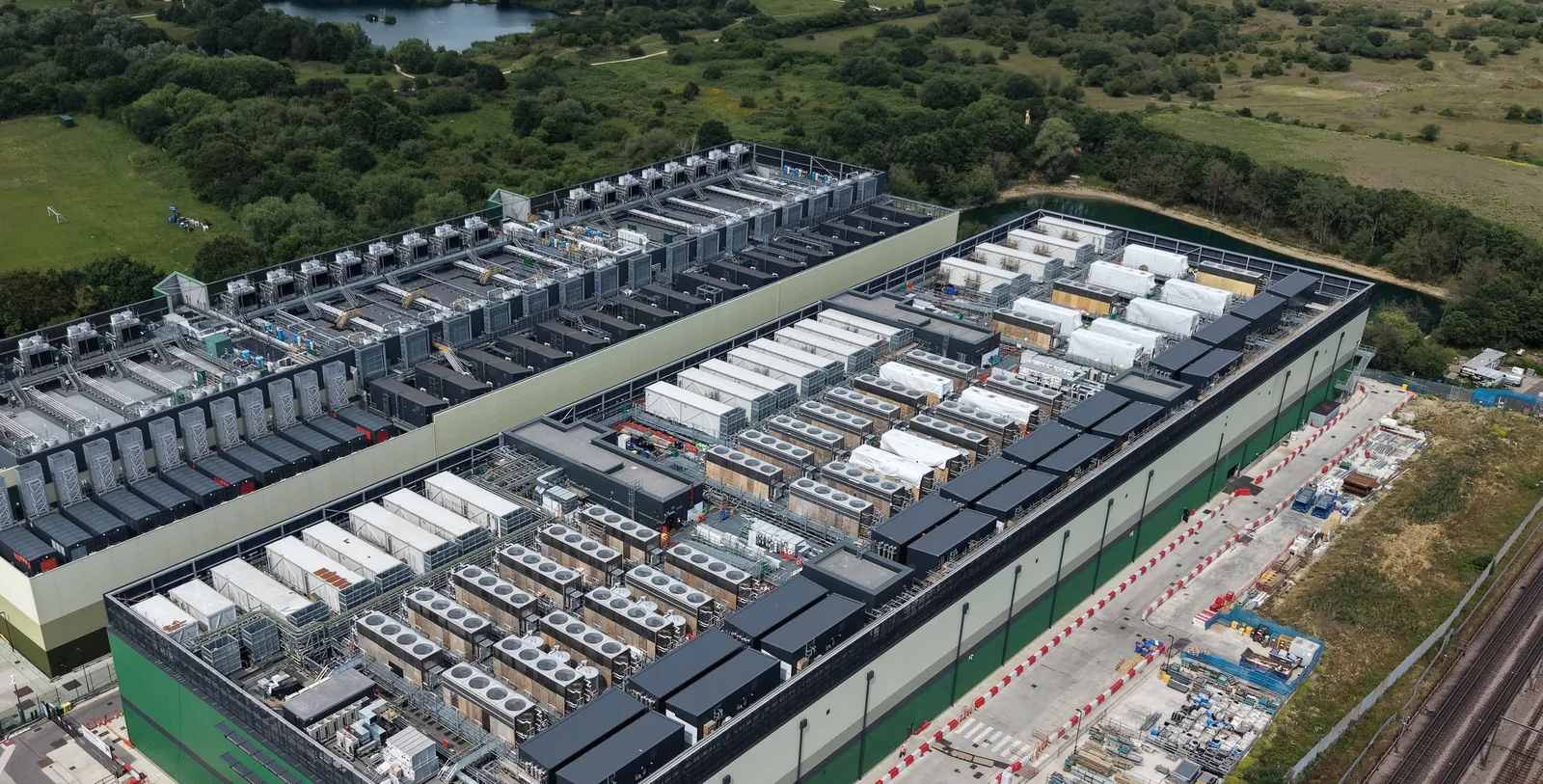 Aerial view of a large data center under construction, with rows of cooling units on the roof